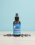 Bottle of Jungle Wellness Lunar Mist on a light blue background with lavender flowers.